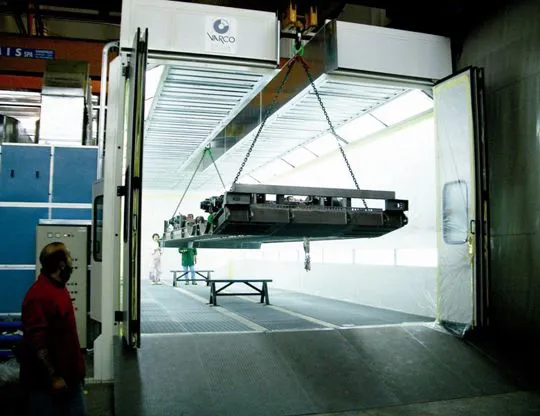Pressurized oven booth on metal basement with dry filtering system and upper opening for inserting pieces with overhead crane