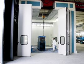 Pressurized oven booth with wet filtering system and upper openings for inserting pieces with overhead crane