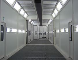 Trzystopniowa ciśnieniowa kabina lakierniczo-susząca o łącznej długości 30 metrów z górnym otworem na całej długości do wstawiania detali za pomocą suwnicy