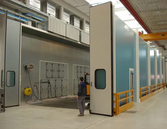 Vista interna della cabina di lavaggio grandi pezzi con quattro gruppi di aspirazione fumane in acciaio inossidabile AISI 304, grigliato totale e sistema di reimmissione aria aspirata con plenum posizionato lateralmente e superiormente alla camera