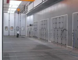  Vista interna della cabina di lavaggio grandi pezzi con quattro gruppi di aspirazione fumane in acciaio inossidabile AISI 304, grigliato totale e sistema di reimmissione aria aspirata con plenum posizionato lateralmente e superiormente alla camera. Nella parete si vedono i portelli per la manutenzione ai gruppi di aspirazione