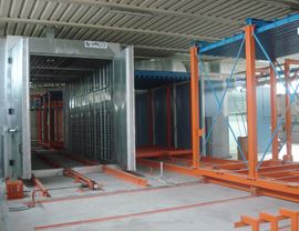 Drying and polymerization oven with bilateral plenums for the distribution of hot air. Handling of pieces with motorized trolleys